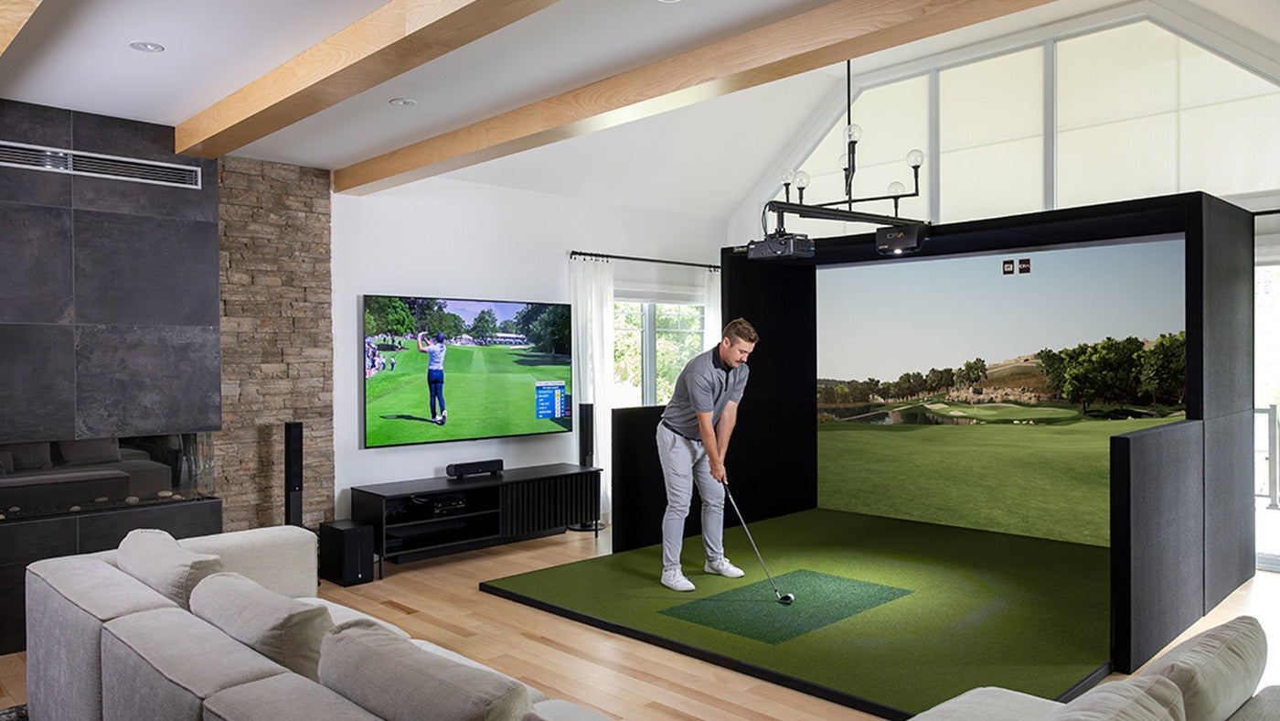 Golfer practicing inside a SimBooth enclosure installed in a home golf room