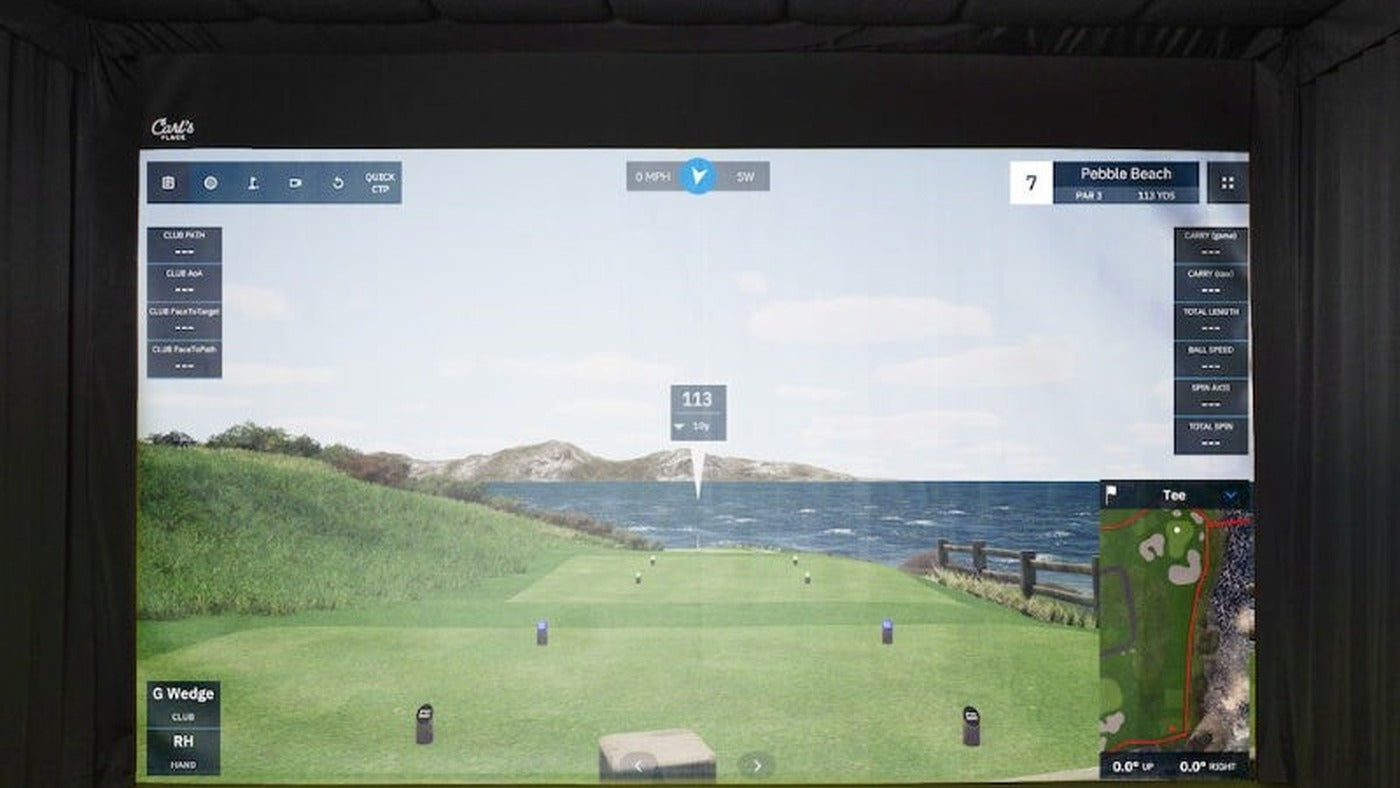 Projected golf course inside an indoor simulator bay with a padded screen surround