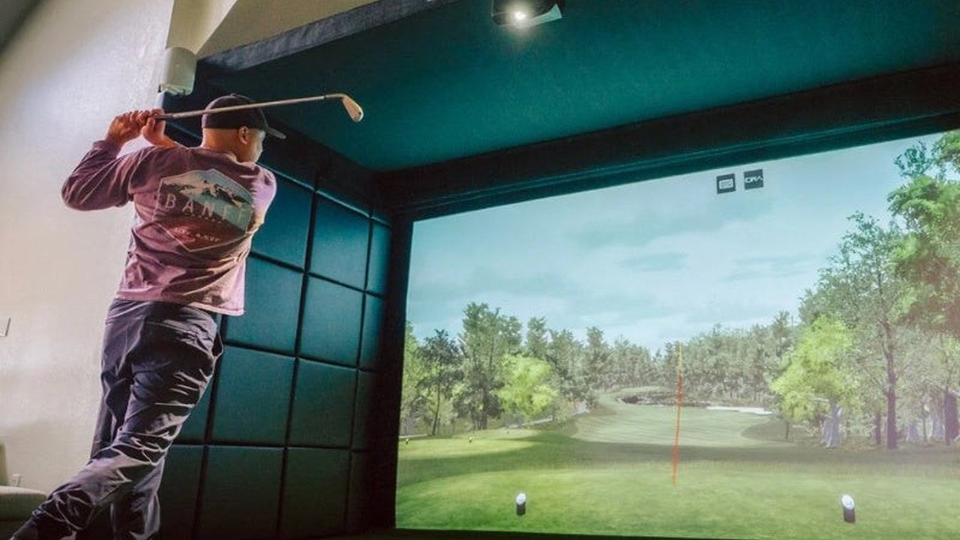 Golfer practicing in an indoor bay with padded walls