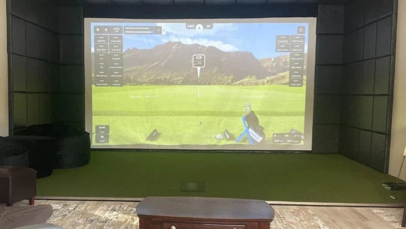 Indoor golf simulator screen in a room with windows and controlled lighting