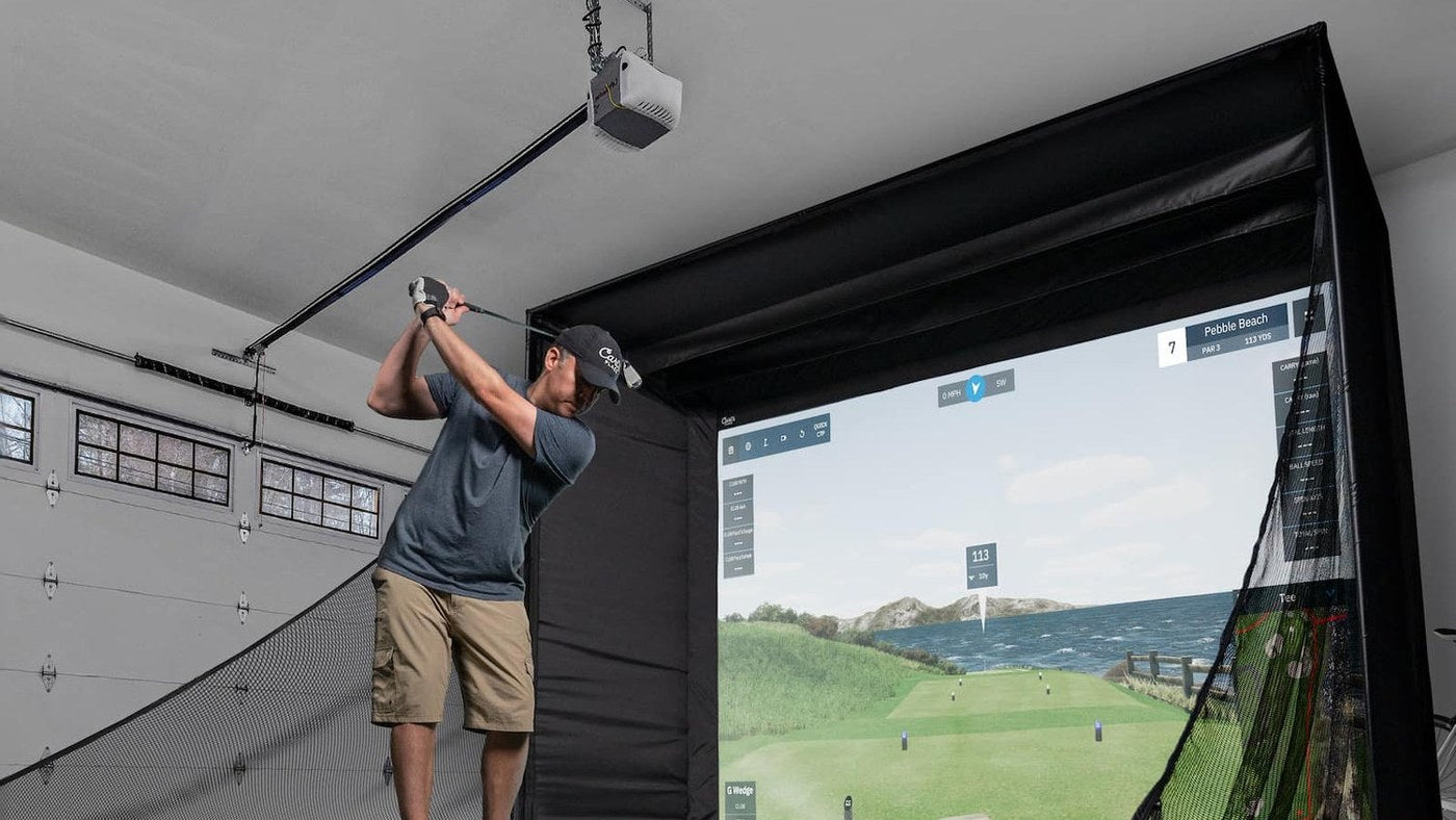 Golfer practicing in a Carl's Place enclosure installed in a garage.
