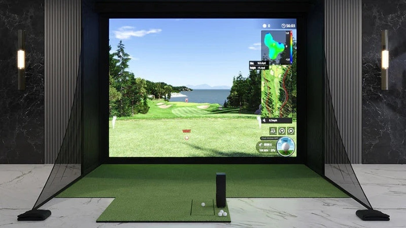 Uneekor EYE MINI LITE in an indoor golf simulator bay with an impact screen and hitting mat